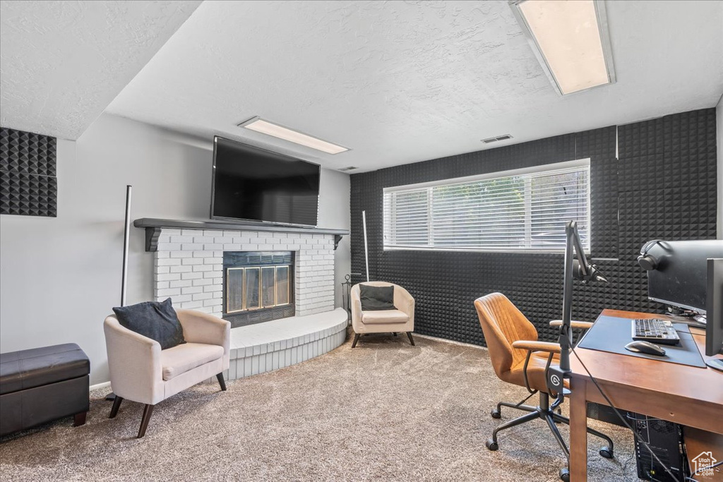 Office area featuring carpet, a textured ceiling, visible vents, and a fireplace