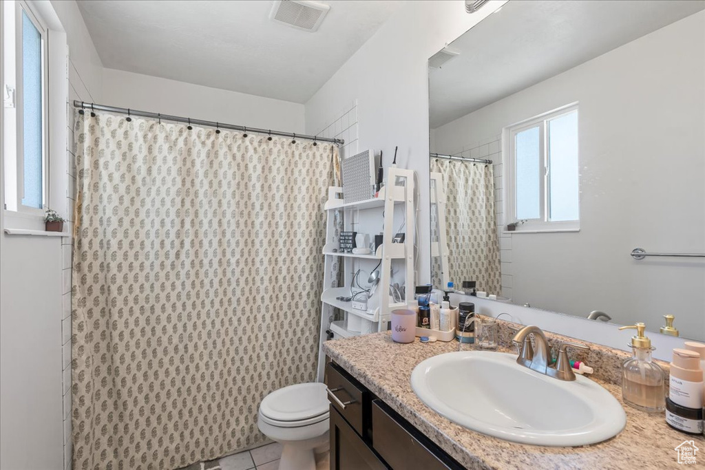 Bathroom with toilet, a shower with curtain, vanity, visible vents, and tile patterned floors