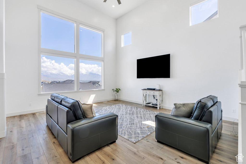Living room featuring a towering ceiling, recessed lighting, a ceiling fan, baseboards, and light wood-style floors
