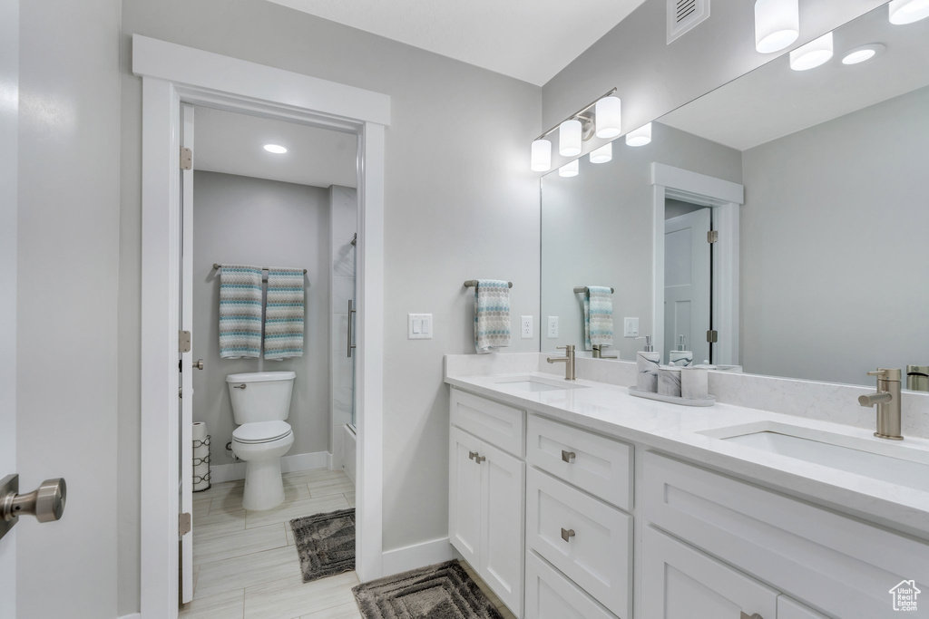 Full bathroom featuring double vanity, toilet, visible vents, and a sink