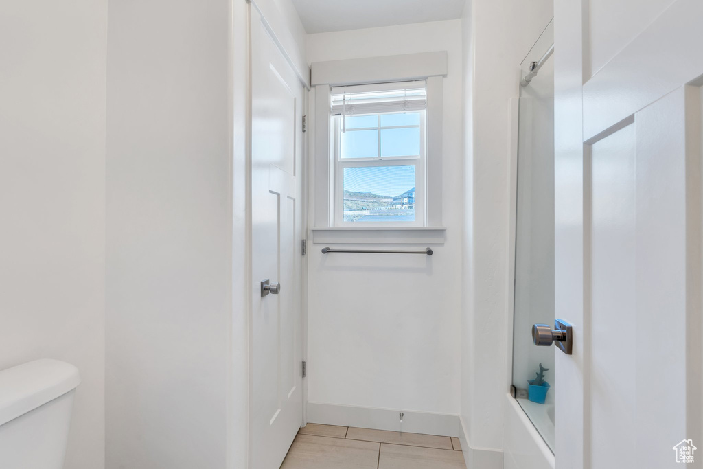 Bathroom featuring tile patterned floors, toilet, a shower, and baseboards