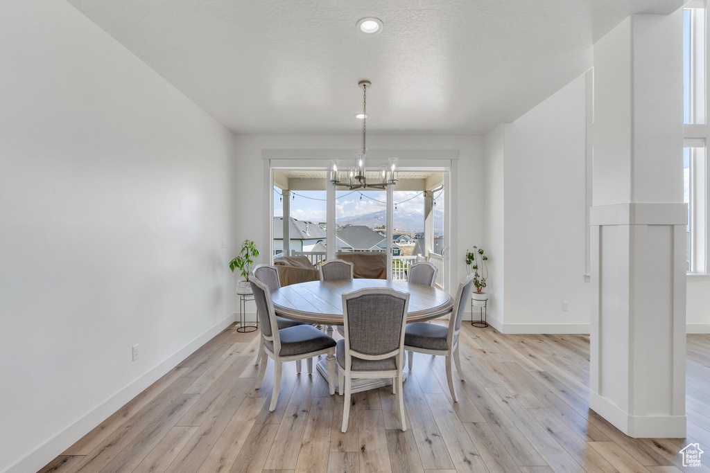 Dining space featuring light wood finished floors, an inviting chandelier, and baseboards