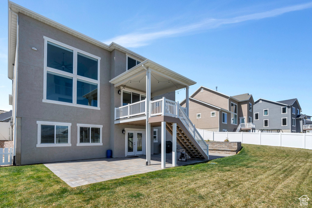 Rear view of property with a yard, stucco siding, french doors, and stairway