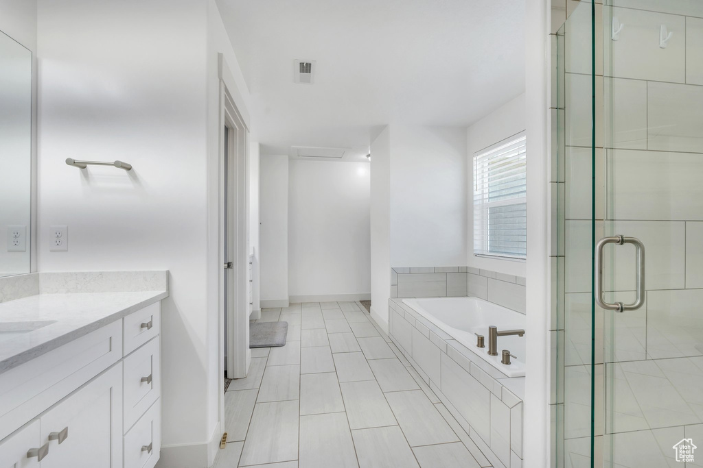 Bathroom with a garden tub, a stall shower, visible vents, baseboards, and vanity