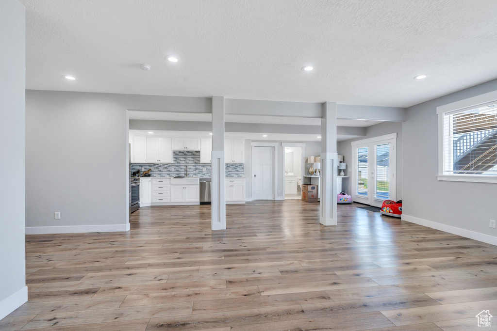 Unfurnished living room with baseboards, recessed lighting, light wood-type flooring, and a textured ceiling