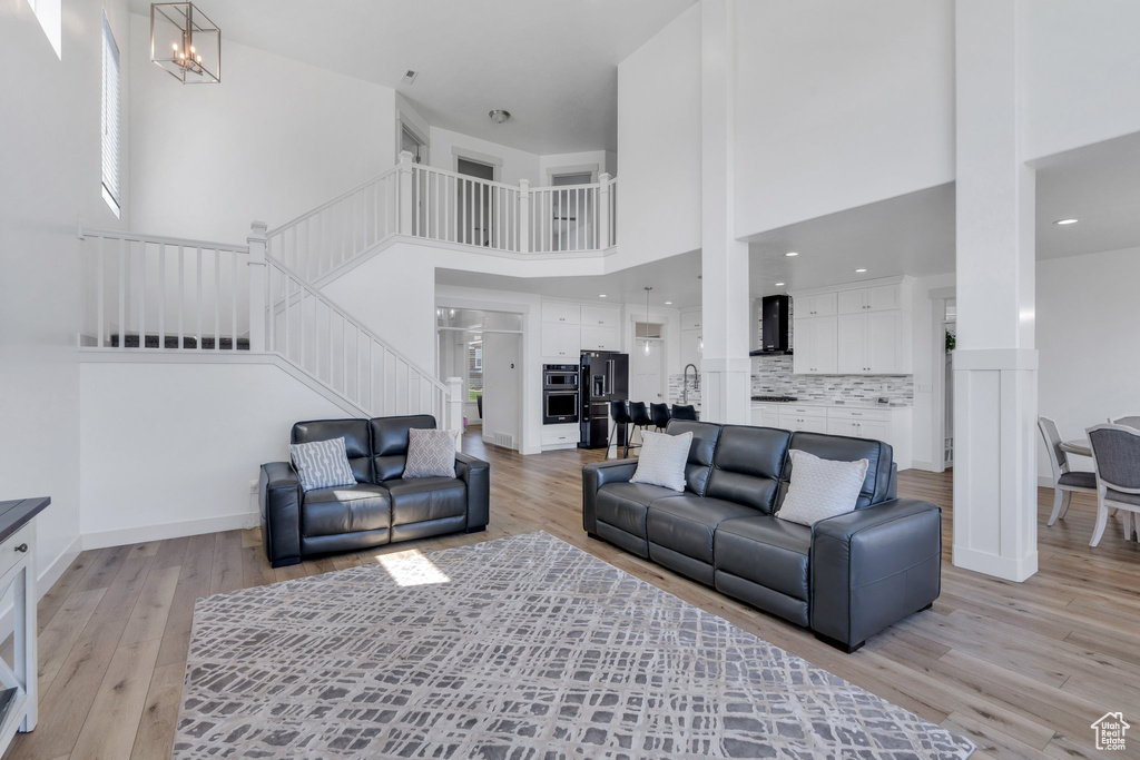 Living room with stairway, a high ceiling, and light wood-style floors