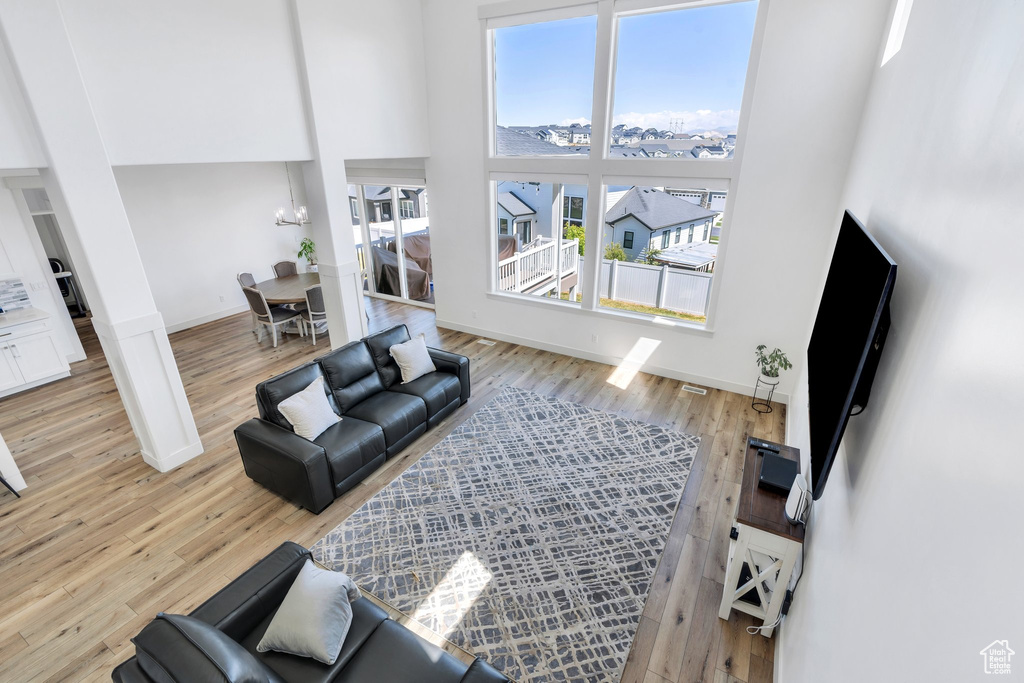 Living room featuring a chandelier, a towering ceiling, baseboards, and light wood finished floors