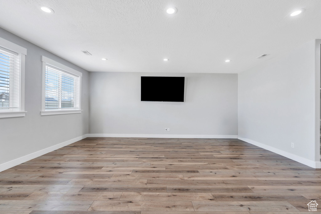 Unfurnished room with wood finished floors, baseboards, and recessed lighting