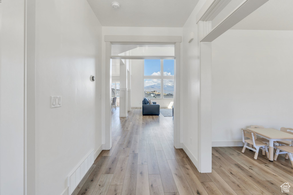 Hallway with baseboards, visible vents, and light wood-style floors