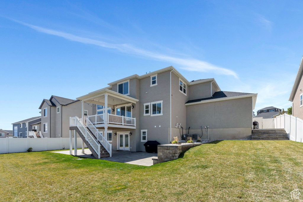 Back of property with a lawn, a patio area, stairs, stucco siding, and a fenced backyard