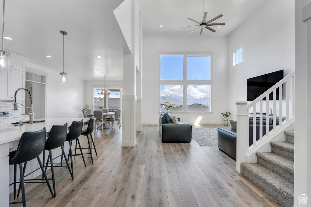 Living room featuring light wood-style flooring, stairway, a towering ceiling, ceiling fan, and recessed lighting