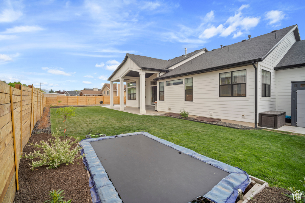Back of property featuring a yard, a shingled roof, a patio area, and a fenced backyard