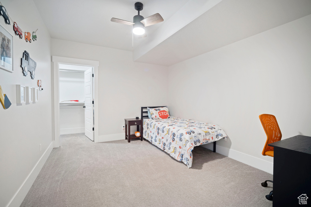 Carpeted bedroom featuring baseboards, ceiling fan, and a walk in closet