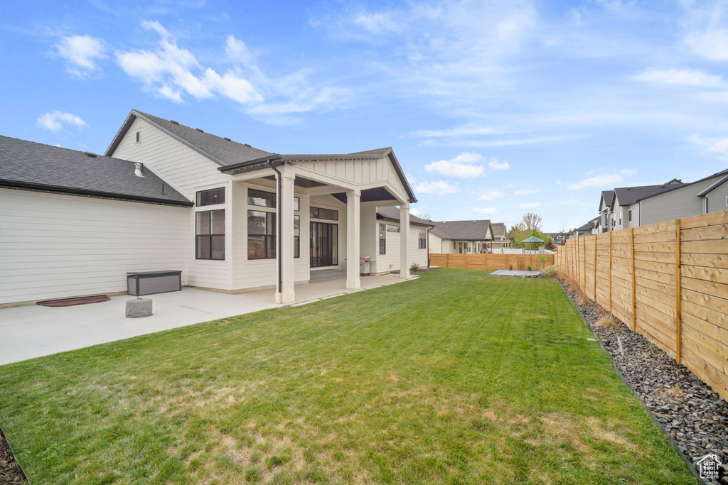 Rear view of property featuring a yard, board and batten siding, a patio area, and a fenced backyard