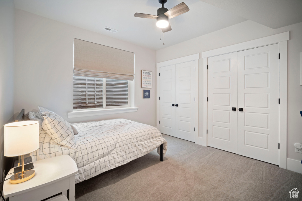 Bedroom with carpet, a ceiling fan, multiple closets, and visible vents