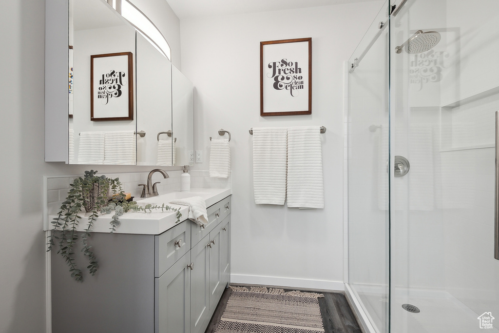 Full bathroom with vanity, baseboards, a stall shower, and wood finished floors