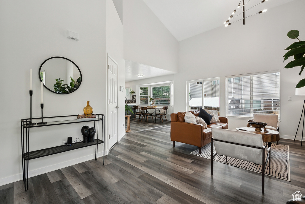 Living area with baseboards, high vaulted ceiling, and wood finished floors