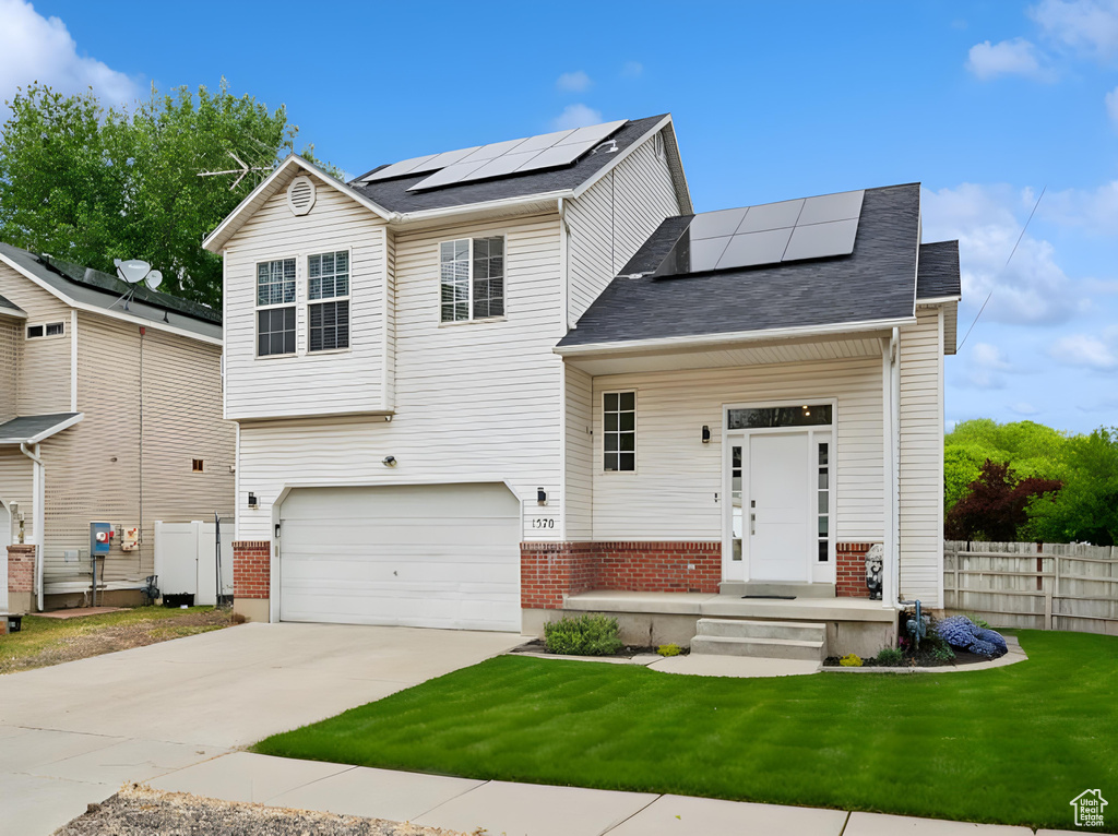 View of front of property with roof mounted solar panels, driveway, a garage, brick siding, and a shingled roof