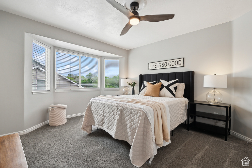Bedroom featuring baseboards, dark colored carpet, and a ceiling fan