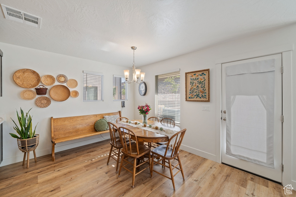 Dining area featuring an inviting chandelier, baseboards, visible vents, and light wood-style floors