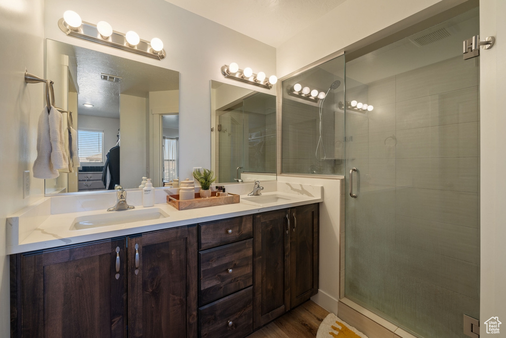Ensuite bathroom featuring a stall shower, visible vents, a sink, and double vanity