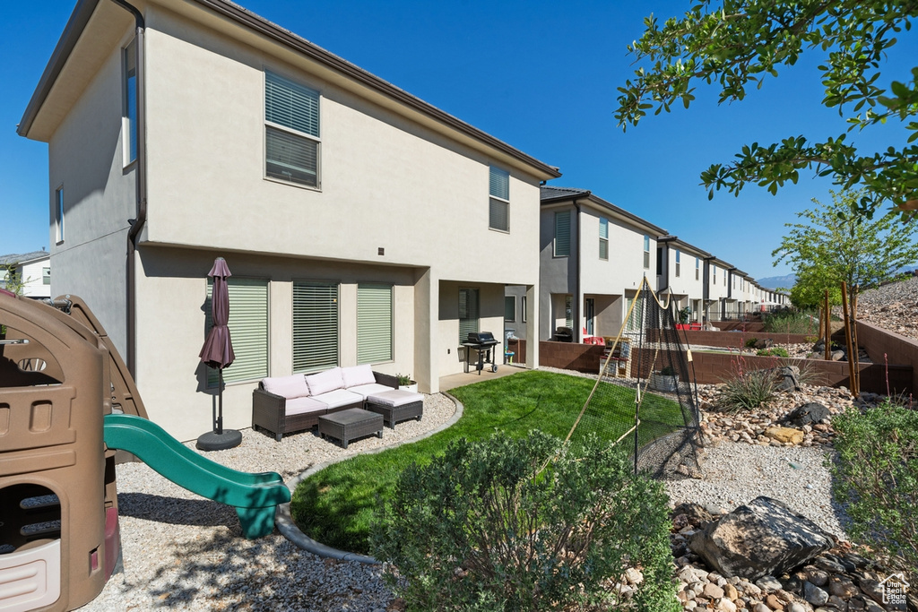 Rear view of house with a playground, stucco siding, a residential view, and a patio