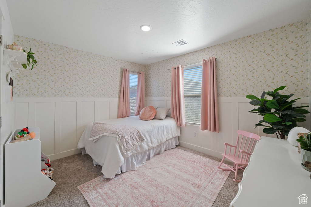 Carpeted bedroom featuring a decorative wall, a wainscoted wall, visible vents, recessed lighting, and wallpapered walls