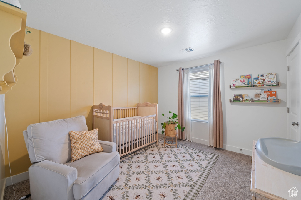 Bedroom with a crib, visible vents, baseboards, and light colored carpet