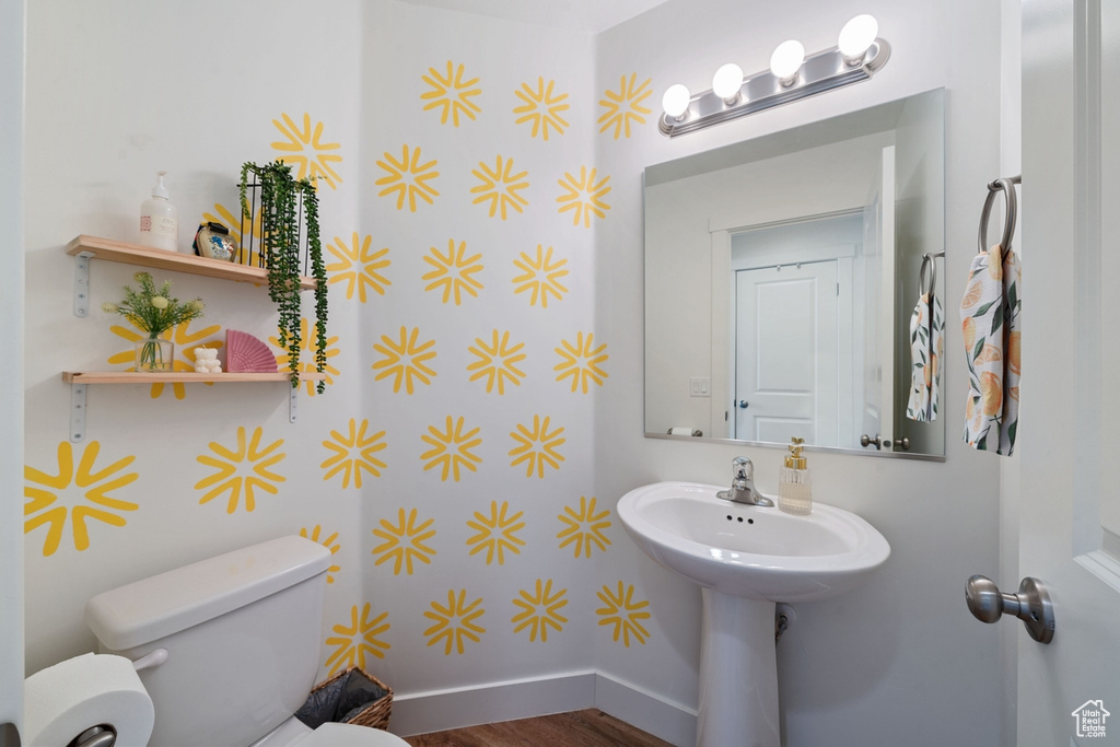 Bathroom with toilet, baseboards, and wood finished floors