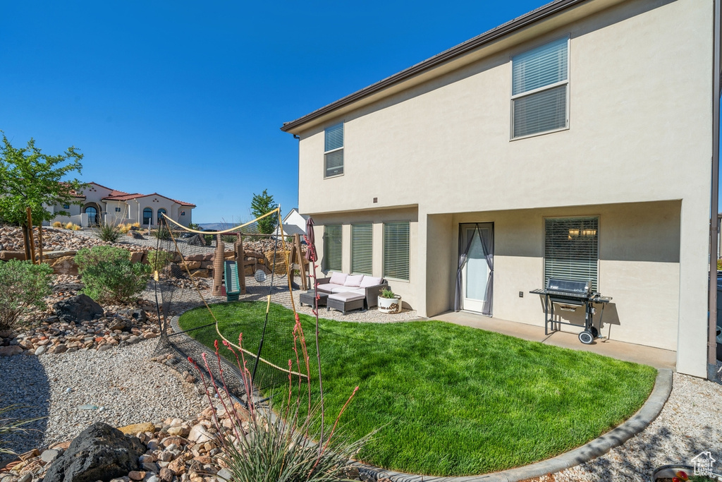 Rear view of property with a yard, stucco siding, a patio, and an outdoor living space