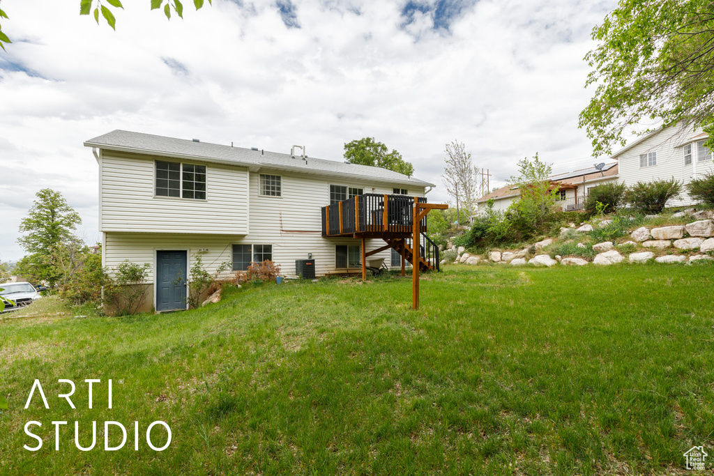 Rear view of house featuring a deck, a yard, central air condition unit, and stairs