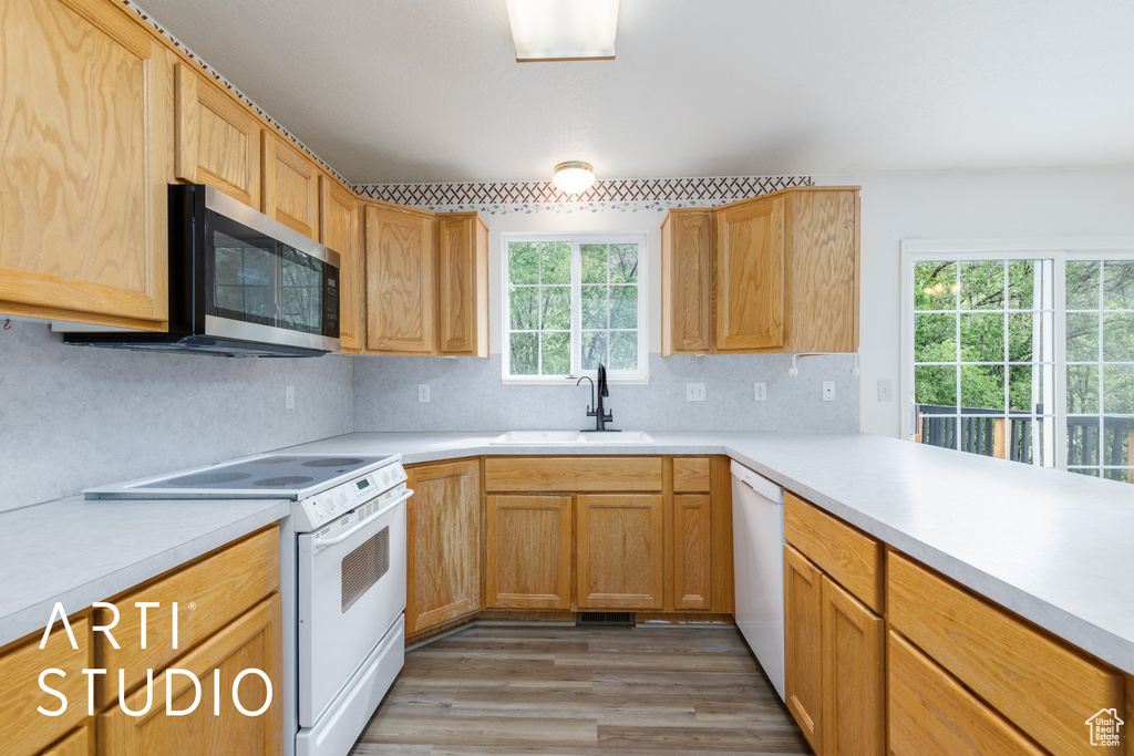 Kitchen featuring white appliances, a sink, light countertops, backsplash, and light wood finished floors