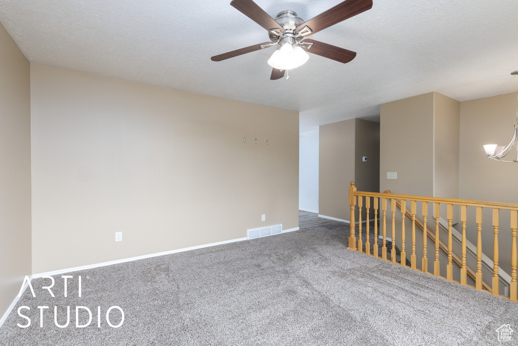 Spare room with carpet, baseboards, a ceiling fan, a chandelier, and a textured ceiling
