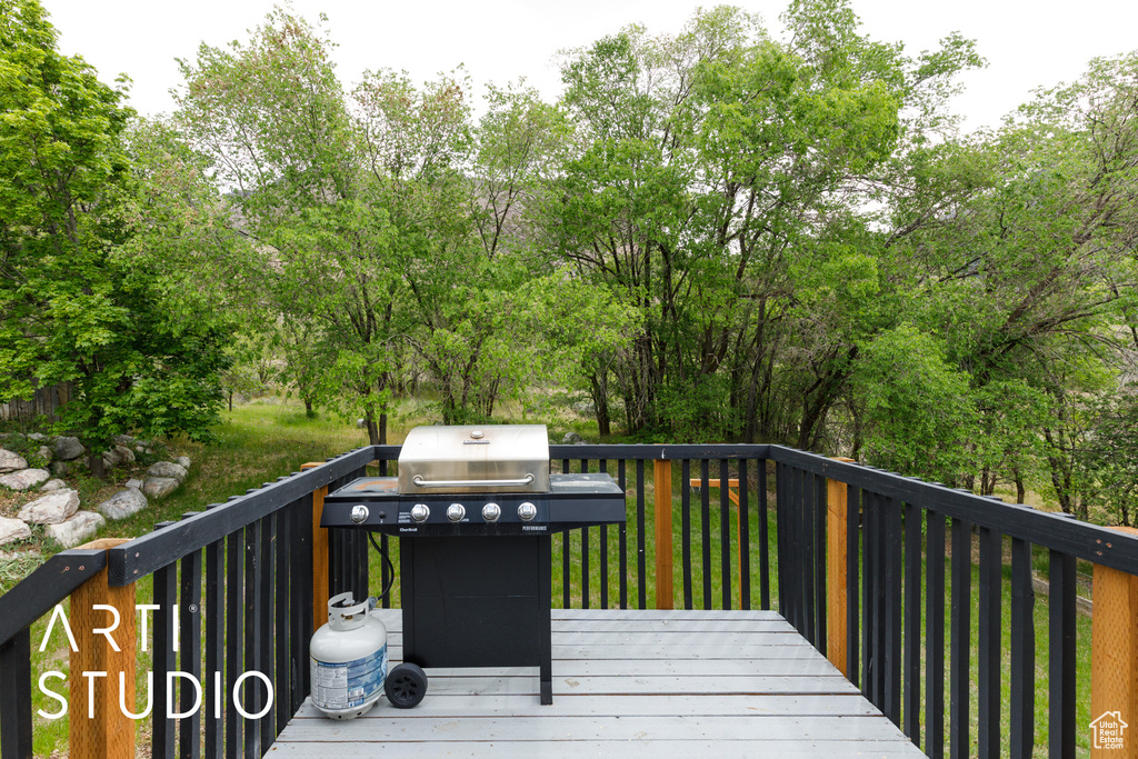 Wooden terrace with area for grilling and view of wooded area