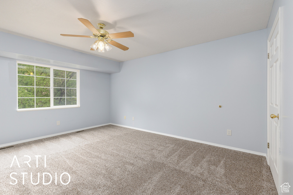 Carpeted spare room featuring ceiling fan and baseboards