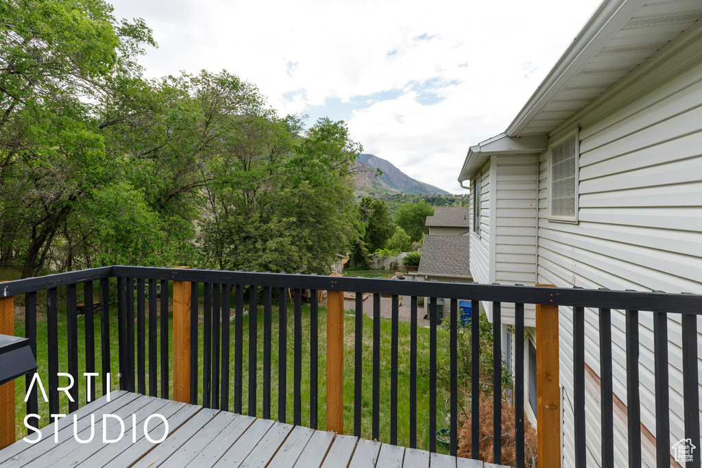 Wooden terrace featuring a mountain view and a yard