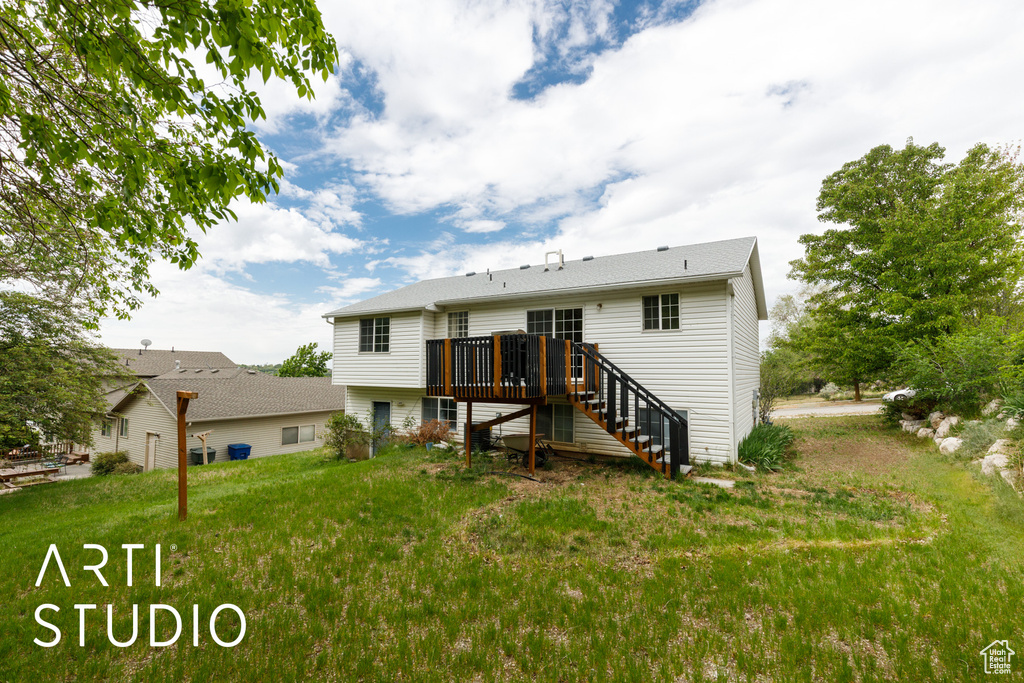 Back of property featuring stairs, a wooden deck, and a lawn
