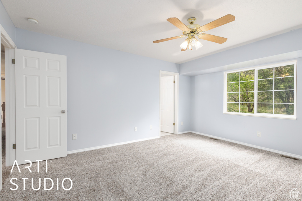Carpeted empty room with baseboards and a ceiling fan