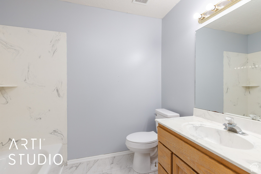 Bathroom with vanity, toilet, marble finish floors, a tub, and baseboards