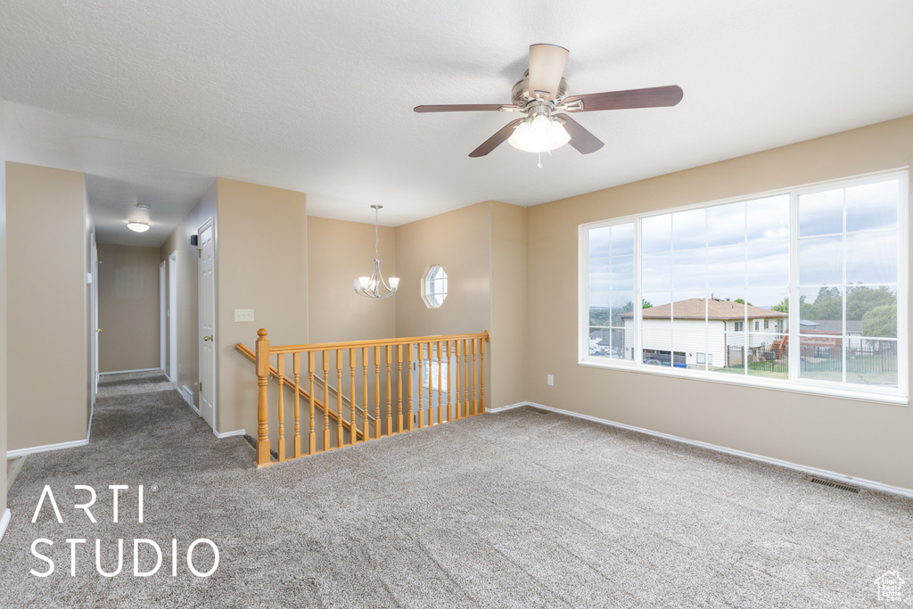 Empty room featuring carpet floors, a chandelier, baseboards, and ceiling fan