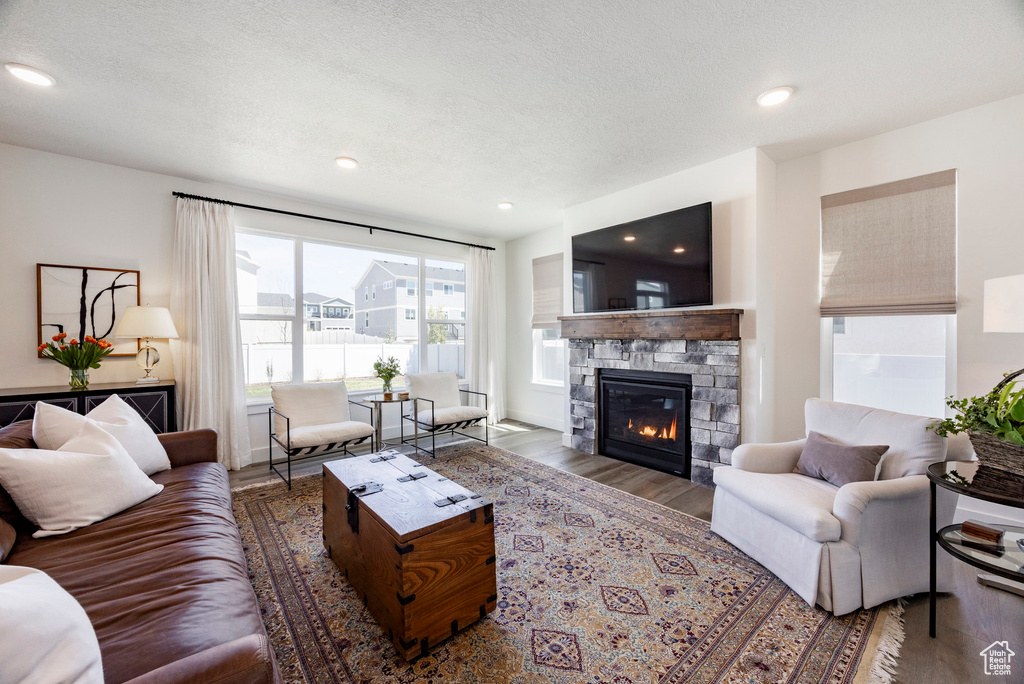 Living room with wood finished floors, a fireplace, a textured ceiling, and recessed lighting