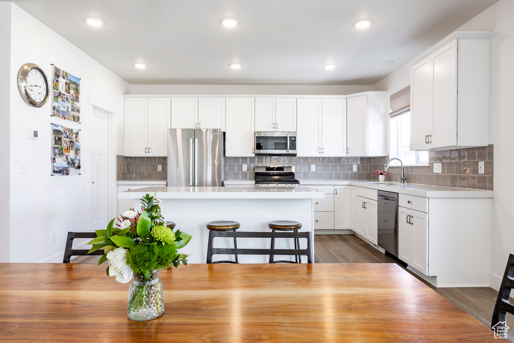 Kitchen featuring appliances with stainless steel finishes, a sink, light countertops, white cabinetry, and recessed lighting