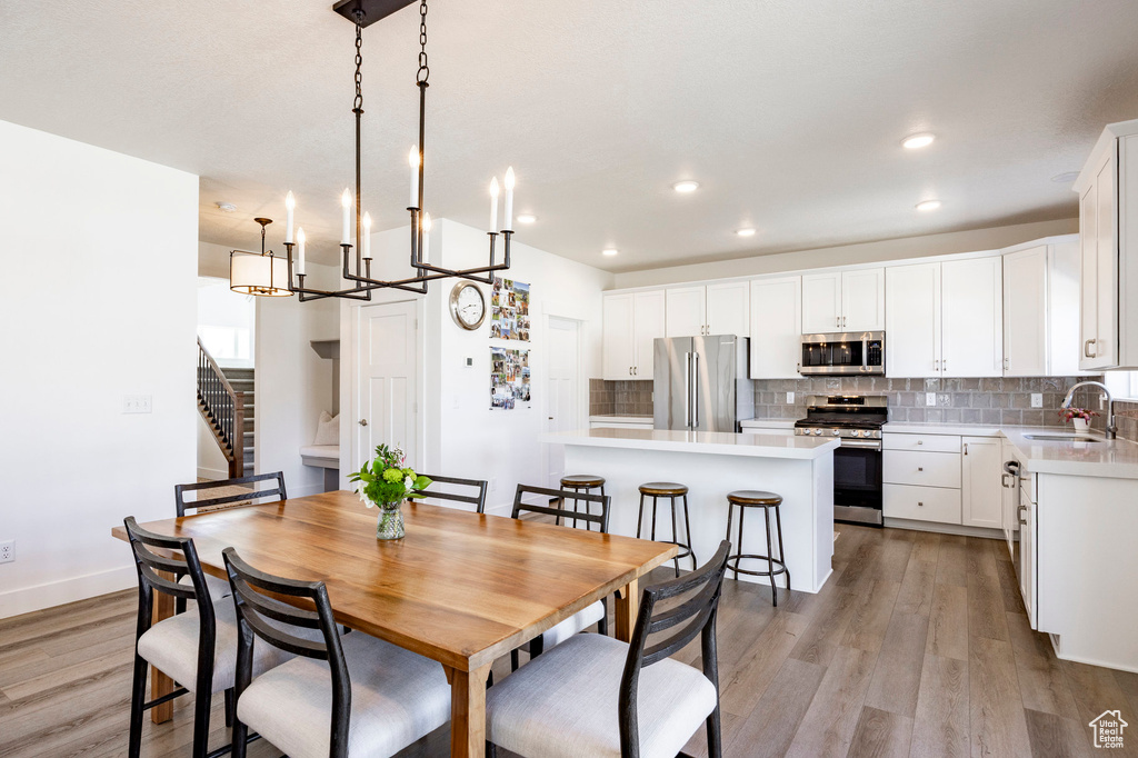 Dining area with light wood-type flooring, stairway, recessed lighting, a chandelier, and baseboards