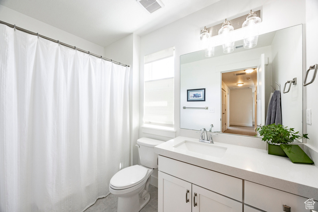 Bathroom with toilet, vanity, and tile patterned floors