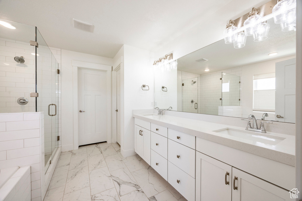 Full bath featuring a stall shower, marble look tiles, and double vanity