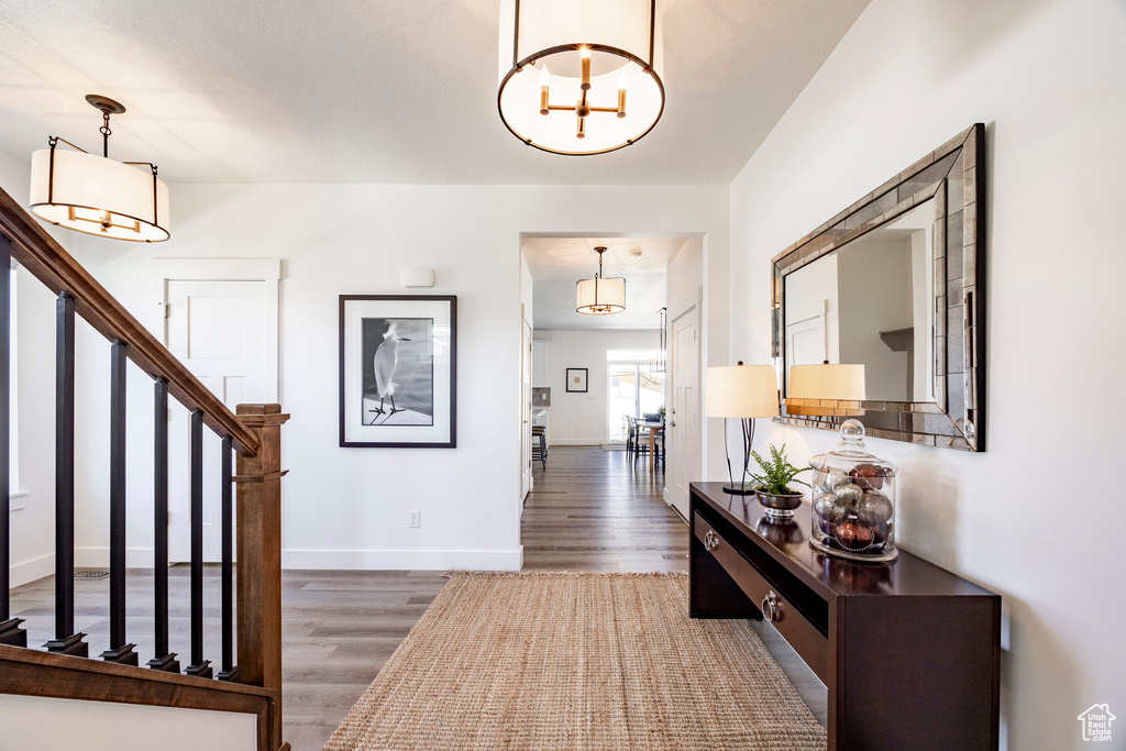 Entryway featuring wood finished floors, stairs, a chandelier, and baseboards