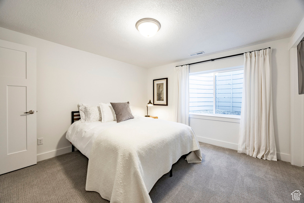 Bedroom with carpet, baseboards, and a textured ceiling
