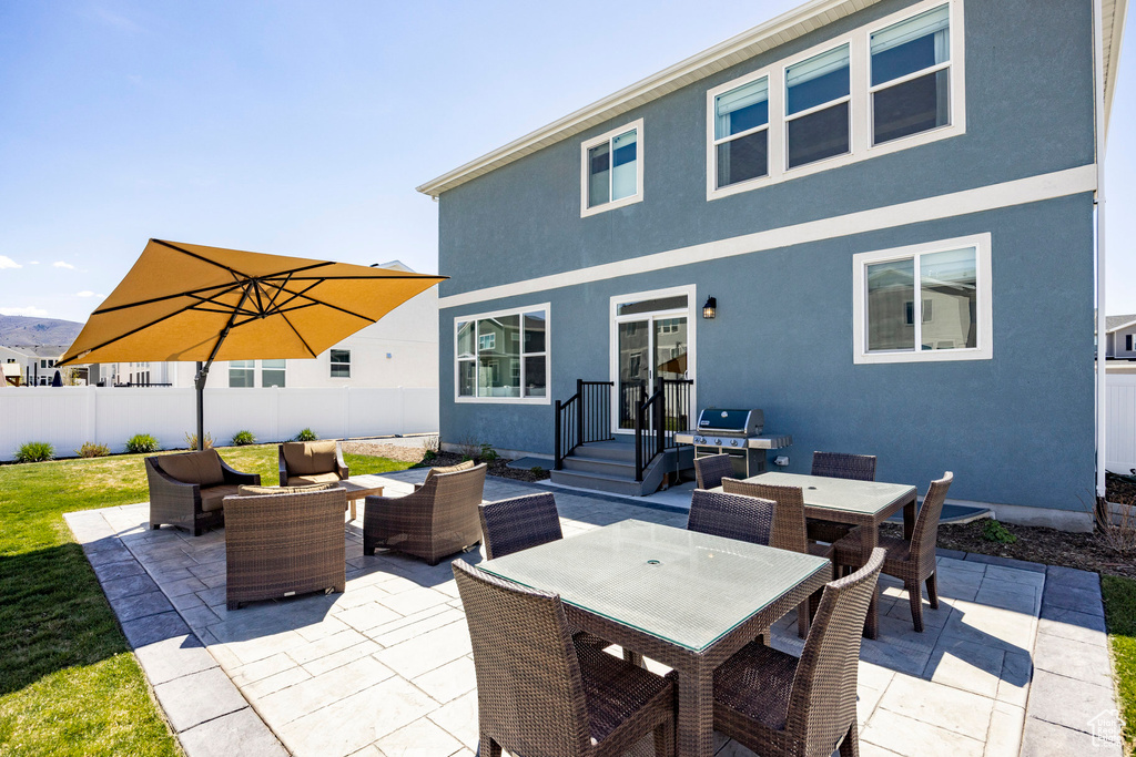 Back of house featuring outdoor lounge area, a patio, outdoor dining area, fence, and stucco siding