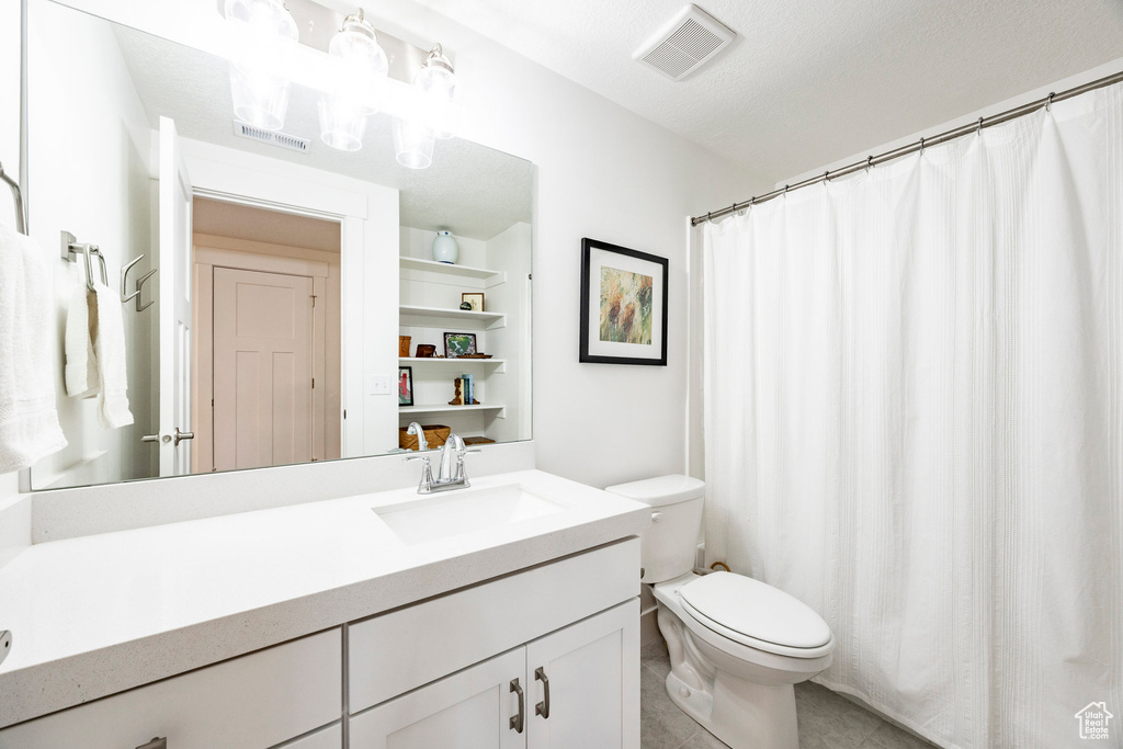 Bathroom with toilet, vanity, tile patterned floors, and built in shelves