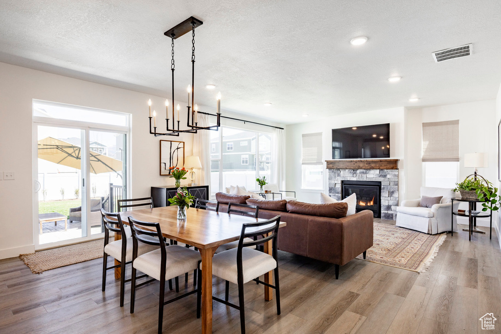 Dining area with wood finished floors, a fireplace, a textured ceiling, a chandelier, and recessed lighting